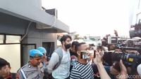 Ammar Zoni dengan tangan diborgol terlihat didampingi oleh beberapa polisi. Foto: Febri/detikHOT