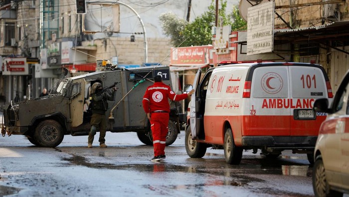 A medic speaks to Israeli soldiers in a military vehicle as they block an ambulance carrying an injured person during an Israeli military raid in Jenin, amid the ongoing conflict between Israel and the Palestinian Islamist group Hamas, in the Israeli-occupied West Bank, December 12, 2023. REUTERS/Raneen Sawafta