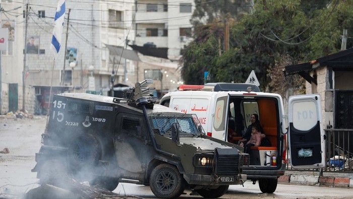 A medic speaks to Israeli soldiers in a military vehicle as they block an ambulance carrying an injured person during an Israeli military raid in Jenin, amid the ongoing conflict between Israel and the Palestinian Islamist group Hamas, in the Israeli-occupied West Bank, December 12, 2023. REUTERS/Raneen Sawafta