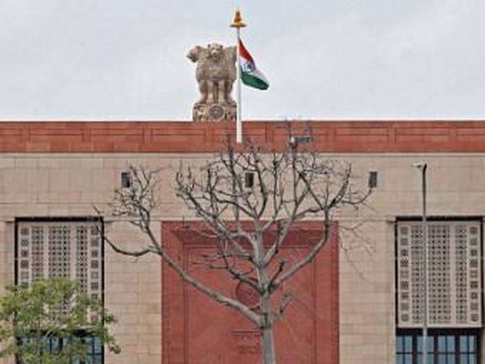 Indias national flag flaps next to the National Emblem at the newly constructed Indian parliament building after the flag hoisting ceremony in New Delhi on September 17, 2023. (Photo by Sajjad HUSSAIN / AFP)