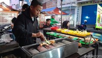 Di lahan jalan yang ukurannya kira-kira sepanjang dua kali lapangan sepak bola ini, para pedagang berjualan. Di sisi kiri dan kanan jalan, gerobak-gerobak pedagang berjejer sehabis asar. Ada yang jualan makanan berat, camilan hingga minuman.