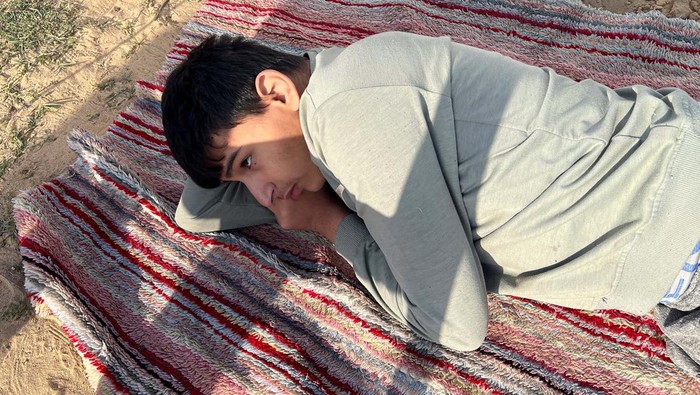 Palestinian autistic teenager Mustasem lays on a carpet, after fleeing his home with his autistic twin Sujood, his mother Asma Abu Abed and his grandmother, due to Israeli strikes, to shelter in a tent in Rafah, in the southern Gaza Strip, December 12, 2023. REUTERS/Saleh Salem