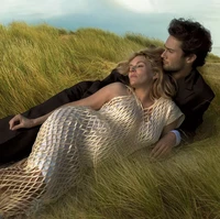 Sienna juga berpose bersama kekasihnya,Oli Green. Dalam foto tersebut, keduanya terlihat tiduran di atas rumput sambil menatap langit. Untuk pose kali ini, wanita berambut pirang itu mengenakan gaun fish net warna beige-putih. Foto: Dok. Vogue