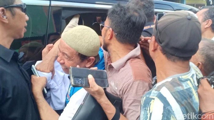 Warga saat berupaya dapat baju yang dibagikan Anies di dalam mobil