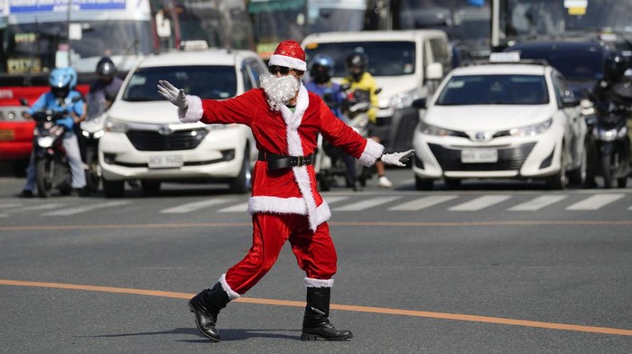 Aksi Unik Sinterklas Menari Atur Lalu Lintas di Jalanan Filipina Filipino traffic enforcer Ramiro Hinojas wears a Santa Claus costume as he directs the flow of vehicles in Pasay city, Philippines on Tuesday, Dec. 5, 2023. Hinojas said he dances during his shift at a busy intersection to bring joy to commuters and pedestrians as the country starts the Christmas season. (AP Photo/Aaron Favila)