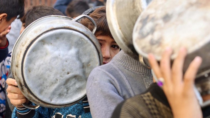 Potret Anak-anak Gaza Antre Makanan Palestinian children hold pots as they queue to receive food cooked by a charity kitchen, amid shortages in food supplies, as the conflict between Israel and Hamas continues, in Rafah in the southern Gaza Strip December 14, 2023. REUTERS/Saleh Salem