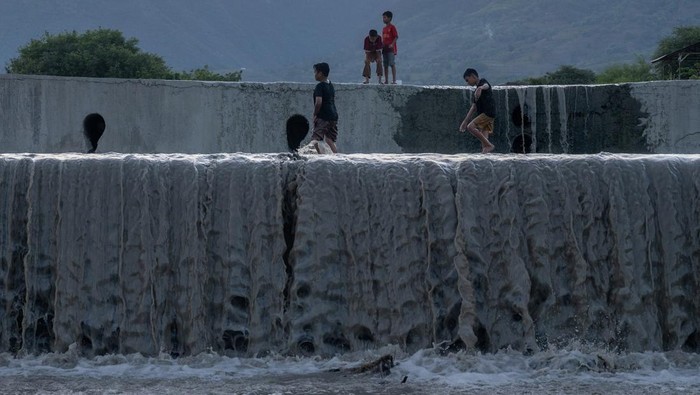 Sejumlah anak bermain di dam pengendali banjir di Duyu, Palu, Sulawesi Tengah, Jumat (15/12/2023). Keterbatasan ruang bermain menyebabkan anak-anak melakukan aktivitas bermain mereka di dam yang berisi air setelah hujan turun di wilayah itu, walaupun kegiatan tersebut cukup berbahaya. ANTARA FOTO/Basri Marzuki/Spt.