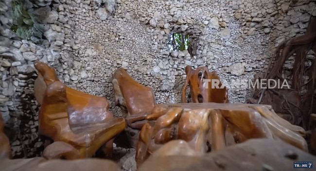 Terdapat semacam goa yang di dalamnya berfungsi sebagai ruang tamu. Adapun bangku dan mejanya terbuat dari belahan batang pohon. (Foto: YouTube/Trans7 Official)