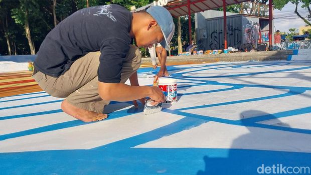 Anggota Komunitas Malang Graffiti Movement mengerjakan gambar grafiti di lantai skate park Merjosari.