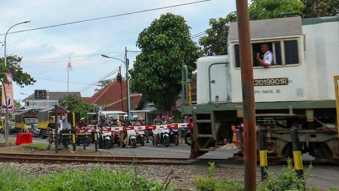 Pengendara bermotor menunggu kereta api melintas dibalik palang pintu yang baru terpasang di Singojuruh, Banyuwangi, Jawa Timur, Sabtu (16/12/2023). Dari 740 perlintasan tanpa palang pintu di Jawa Timur, Dinas Perhubungan provinsi telah membangun 37 palang pintu di tambah 34 palang pintu dibangun oleh pemerintah Kabupaten-kota sebagai upaya meningkatkan keselamatan bagi penggunaan jalan. ANTARA FOTO/Budi Candra Setya/rwa.