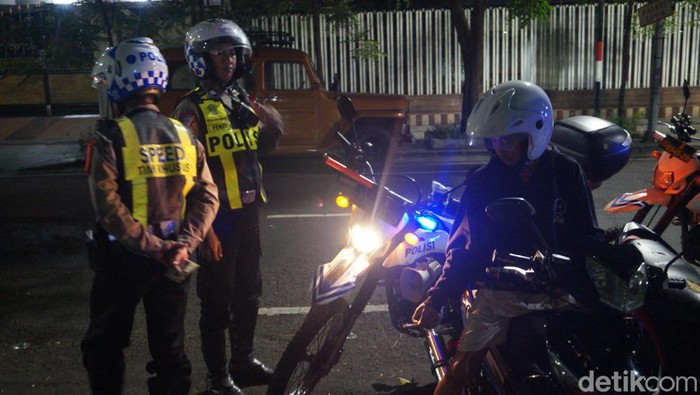 Polisi menilang pemotor yang menggunakan knalpot brong di Jalan Tunjungan Surabaya.
