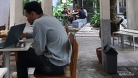 Para pelanggan sedang bersantai sambil menikmati kopi dan makanan.