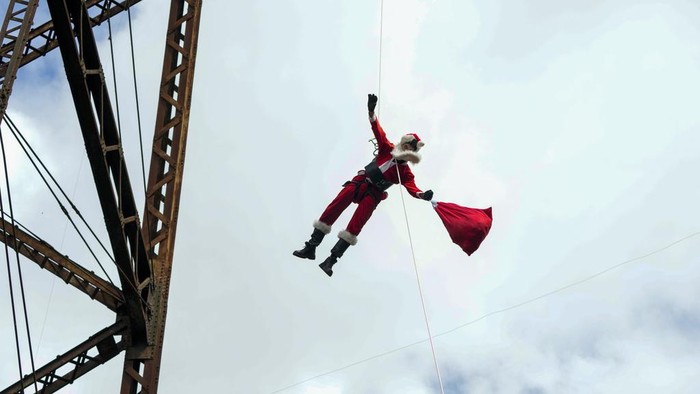 Firefighter Hector Chacon, dressed as Santa Claus, rappels down to give out Christmas gifts to children on the outskirts of Guatemala City on Sunday, Dec. 17, 2023. Since 1997, Chacon has been collecting toys to give at Christmas. (AP Photo/Moises Castillo)