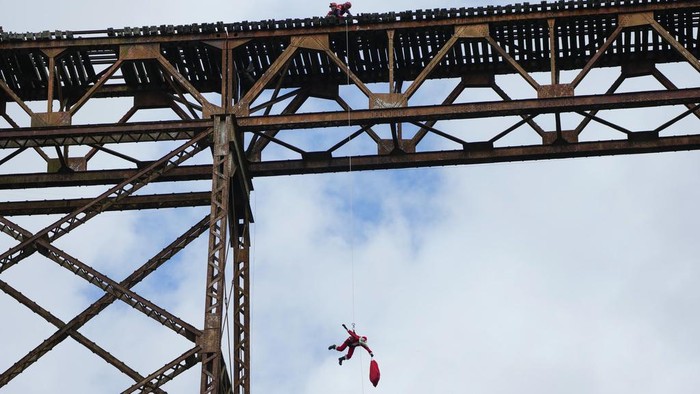 Aksi 'Sinterklas' Terjun dari Jembatan untuk Bagikan Hadiah kepada Anak-anak Firefighter Hector Chacon, dressed as Santa Claus, rappels down to give out Christmas gifts to children on the outskirts of Guatemala City on Sunday, Dec. 17, 2023. Since 1997, Chacon has been collecting toys to give at Christmas. (AP Photo/Moises Castillo)