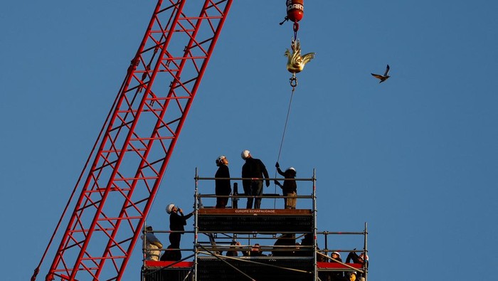 A crane raises the new rooster to install it at the top of the spire of the Notre-Dame de Paris Cathedral, which was ravaged by a fire in 2019 that sent its spire crumbling down, as restoration works continue in Paris, France, December 16, 2023. REUTERS/Christian Hartmann