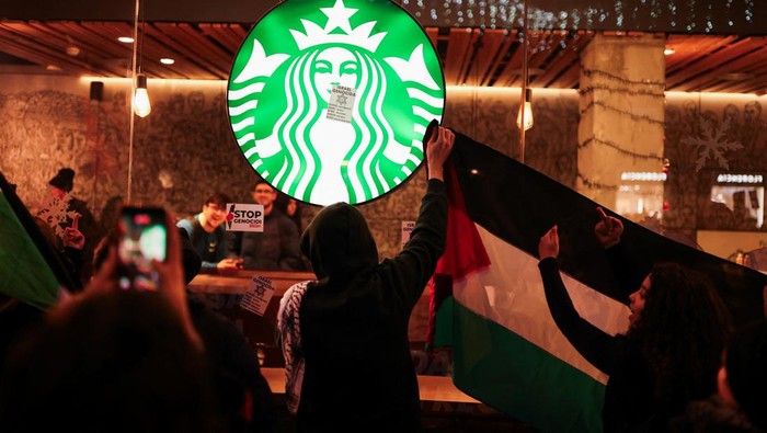 Momen Starbucks Barcelona Digeruduk Massa Pro-Palestina SENSITIVE MATERIAL. THIS IMAGE MAY OFFEND OR DISTURB A person waves a Palestinian flag in front of a Starbucks coffee shop as they take part in a demonstration in support of Palestinians, demanding an immediate ceasefire in Gaza, amid the ongoing conflict between Israel and the Palestinian Islamist group Hamas, in Barcelona, Spain, December 16, 2023. REUTERS/Nacho Doce