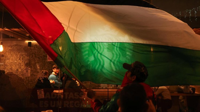 Momen Starbucks Barcelona Digeruduk Massa Pro-Palestina SENSITIVE MATERIAL. THIS IMAGE MAY OFFEND OR DISTURB A person waves a Palestinian flag in front of a Starbucks coffee shop as they take part in a demonstration in support of Palestinians, demanding an immediate ceasefire in Gaza, amid the ongoing conflict between Israel and the Palestinian Islamist group Hamas, in Barcelona, Spain, December 16, 2023. REUTERS/Nacho Doce