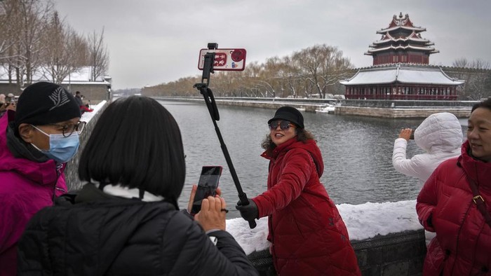 Potret Ribuan Orang Berdesakan untuk Lihat Salju di Kota Terlarang China A woman takes a selfie with the Turret of the Forbidden City after a snow fall in Beijing, Monday, Dec. 11, 2023. Throngs of people in down parkas and boots climbed a hill that overlooks the Forbidden City this week to jostle with others trying to get a shot of the snow-covered roofs of the former imperial palace.(AP Photo/Andy Wong)