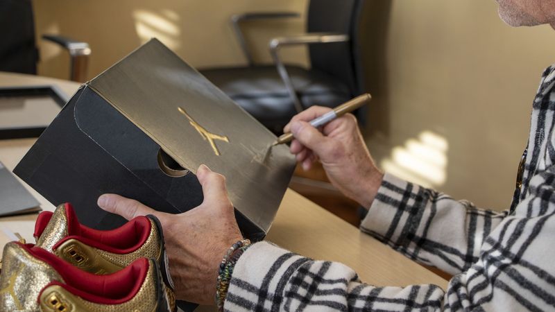 This photo provided by the Portland Rescue Mission shows James Free posing for a photo with a pair of of gold Nike Air Jordan 3 sneakers at the Portland Rescue Mission on Sunday, Oct. 30, 2023, in Portland, Ore.  A pair of rare Nike sneakers donated to a homeless shelter in Portland, Oregon, are up for auction and are expected to raise as much as $20,000. Why? They were custom-made for filmmaker Spike Lee. (Aaron Ankrom/Portland Rescue Mission via AP)