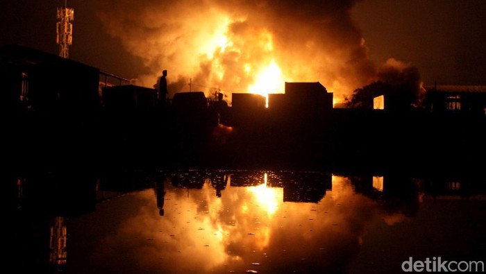 Warga menyaksikan gudang tiner yang terbakar di Kalianak, Surabaya, Jawa Timur, Senin (18/12/2023). Sebanyak 30 kendaraan pemadam kebakaran dari Dinas Pemadam Kebakaran dan Penyelamatan (DPKP) Kota Surabaya dikerahkan untuk memadamkan kebakaran yang mengakibatkan enam orang pekerja di tempat itu mengalami luka bakar. ANTARA FOTO/Didik Suhartono/foc.