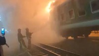 Momen saat petugas berusaha memadamkan api dari gerbong kereta yang dibakar.  