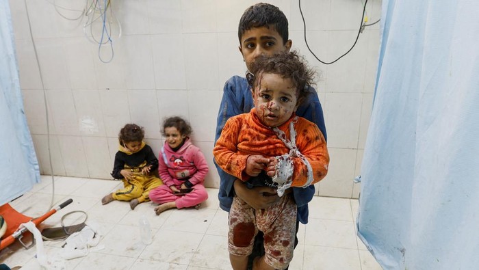 A Palestinian boy carries a wounded child at Nasser hospital following Israeli strikes, amid the ongoing conflict between Israel and Palestinian Islamist group Hamas, in Khan Younis in the southern Gaza Strip, December 9, 2023. REUTERS/Ibraheem Abu Mustafa