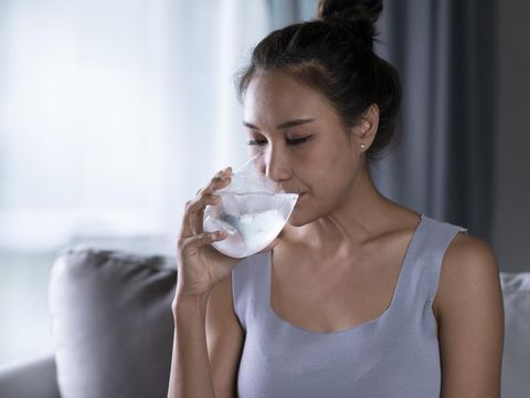 Young Asian woman drinking pure water with ice from glass. Female drinking from a glass of water. Health care concept
