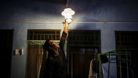 Peternak menyalakan lampu yang menggunakan energi dari limbah kotoran sapi.
