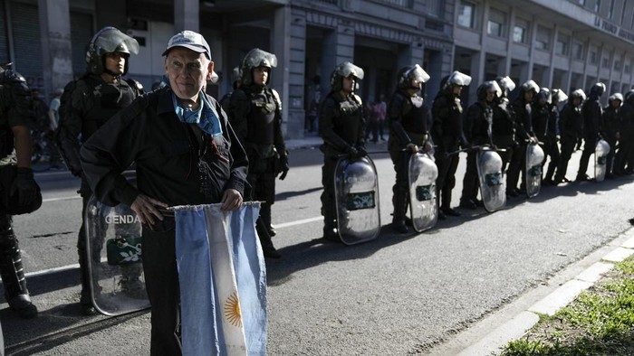 A retiree who said he voted for President Javier Milei stands in support of security forces deployed during protests against economic measures in downtown Buenos Aires, Argentina, Wednesday, Dec. 20, 2023. (AP Photo/Rodrigo Abd)