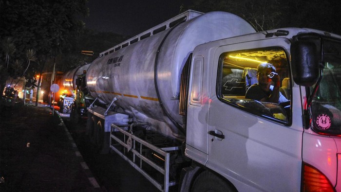 Warga berjalan diantara truk yang antre saat pengisian BBM di salah satu SPBU di Kota Cilegon, Banten, Rabu (20/12/2023). Para supir truk di daerah tersebut mengaku kesulitan mendapatkan BBM jenis solar yang terjadi di hampir seluruh SPBU di Kota Cilegon, hingga mengharuskan mereka antre berjam-jam dan menyebabkan kemacetan panjang. ANTARA FOTO/Muhammad Bagus Khoirunas/foc.