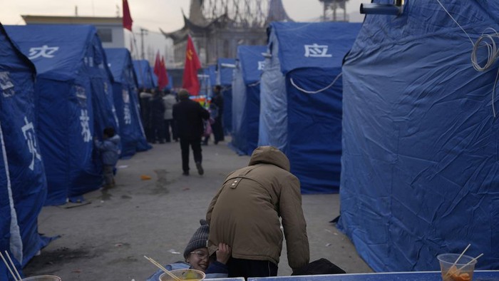 Penampakan Lokasi Pengungsian Korban Gempa China A child stands near tents at a temporary shelter after an earthquake in Dahejia town in northwestern China's Gansu province, Wednesday, Dec. 20, 2023. A strong overnight earthquake rattled a mountainous region of northwestern China, authorities said Tuesday, destroying homes, leaving residents out in a below-freezing winter night and killing many in the nation's deadliest quake in nine years. (AP Photo/Ng Han Guan)
