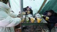 Warga korban gempa menyantap makanan instan selagi panas untuk menghangatkan tubuh di tengah dinginnya udara saat di pengungsian.  