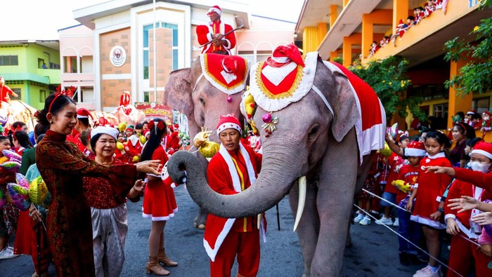 Teachers and students wait for gifts from elephants dressed in Santa Claus costumes ahead of Christmas celebrations at a primary school, in Ayutthaya, Thailand, December 22, 2023. REUTERS/Artorn Pookasook