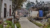 Warga melintas di dekat rumah yang telah terbakar di Kampung Karian, Lebak, Banten, Jumat (22/12/2023). 