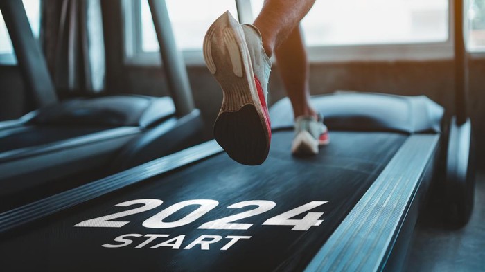 Happy new year 2024,2024 symbolizes the start of the new year. Close up of feet, sportsman runner running on treadmill in fitness club. Cardio workout. Healthy lifestyle, guy training in gym.