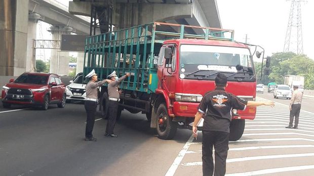 Petugas kepolisian menilang kendaran angkutan barang di tol menuju Cikampek. (X @TMCPoldaMetro)