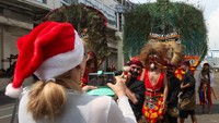 Wisatawan asing memotret seniman reog usai turun dari kapal pesiar Seven Seas Navigator yang bersandar di Dermaga Jamrud Utara, Pelabuhan Tanjung Perak, Surabaya, Jawa Timur, Senin (25/12/2023).