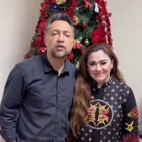 Pasangan Ari Sihasale dan Nia Zulkarnaen merayakan Natal di Papua. Keduanya berpose dengan latar pohon Natal yang dekorasinya meriah bernuansa merah. Foto: dok. Instagram Ari Sihasale