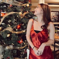 Cassandra Lee tampil dengan shift dress merah dipadu dalaman warna hitam. Sebagai pelengkap penampilan, aktris 22 tahun ini memakai anting loop dan kalung. Cassandra tampak berpose di samping pohon Natal. Foto: Instagram