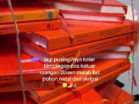 Mahasiswi melihat tumpukan skrip yang dibentuk menjadi pohon natal.