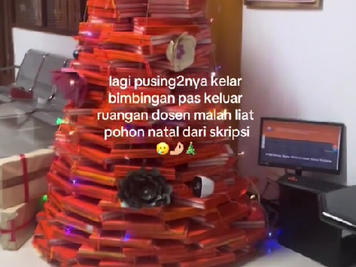 Mahasiswi melihat tumpukan skrip yang dibentuk menjadi pohon natal.