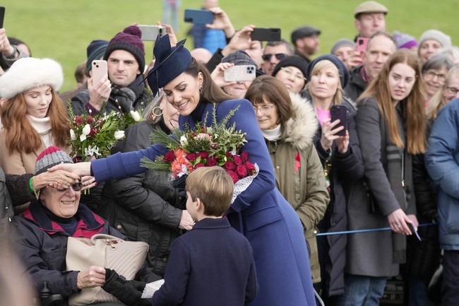 Seusai ibadah, Pangeran Louis menemani ibunya menyapa warga yang telah menanti mereka. Antusias, warga setempat juga memberi bunga dan kado untuk keluarga Kerajaan. Pangeran Louis pun tak kelawatan mendapat hadiah. (Foto: AP Photo/Kin Cheung)