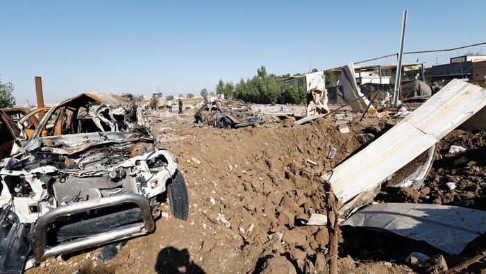 Fighters of the Iraqi Kataib Hezbollah militia group and a man inspect the site of a U.S. airstrike, in Hilla, Iraq December 26, 2023. REUTERS/Alaa al-Marjani