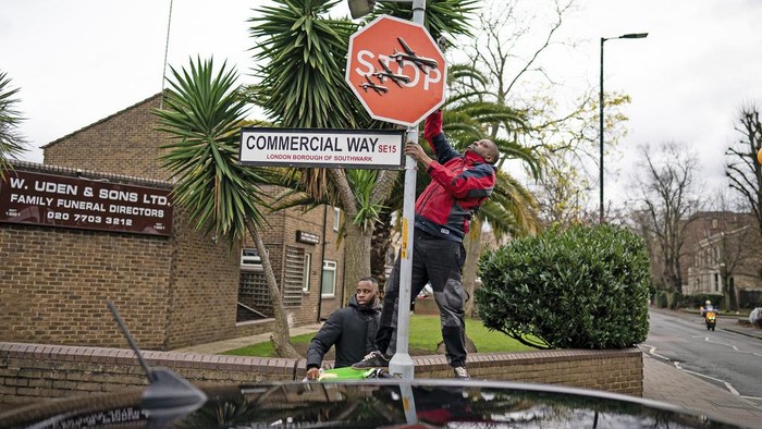 Detik-detik Karya Seni Banksy Dukung Palestina Dicuri di Inggris A person removes a piece of art work by Banksy, which shows what looks like three drones on a traffic stop sign, which was unveiled at the intersection of Southampton Way and Commercial Way in Peckham, south east London, Friday Dec. 22, 2023. (Aaron Chown/PA via AP)