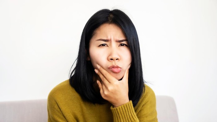 depressed Asian woman having problem with Bells Palsy/Facial Palsy, hand holding her face