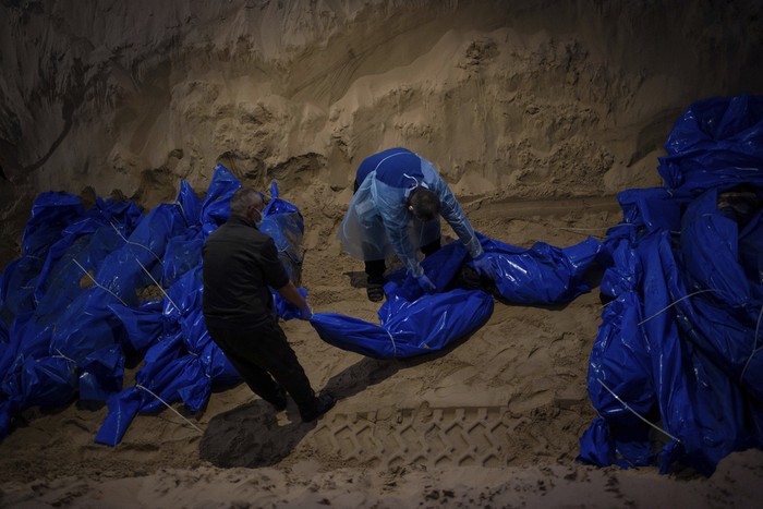 Medics unload the bodies of Palestinians killed in fighting with Israel and turned over by the Israeli military during a mass funeral in Rafah, Gaza Strip, Tuesday, Dec. 26, 2023.(AP Photo/Fatima Shbair)
