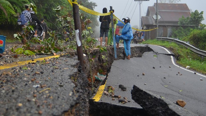 Warga berada di dekat jalan yang amblas di kelok 17 Koto Alam, Limapuluhkota, Sumatera Barat, Rabu (27/12/2023). Intensitas hujan tinggi sejak Senin (25/12) membuat ruas jalan utama menuju provinsi Riau itu amblas dan longsor sehingga arus lalu-lintas tersendat karena diberlakukan sistem buka-tutup. ANTARA FOTO/Iggoy el Fitra/Spt.