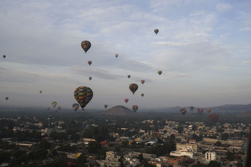 Hot air balloons teeming with tourists fly over the Sun pyramid at the Teotihuacan archaeological site, just north of Mexico City, Sunday, Dec. 24, 2023. (AP Photo/Marco Ugarte)