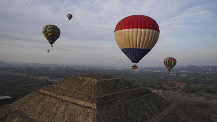 Hot air balloons teeming with tourists fly over the Sun pyramid at the Teotihuacan archaeological site, just north of Mexico City, Sunday, Dec. 24, 2023. (AP Photo/Marco Ugarte)
