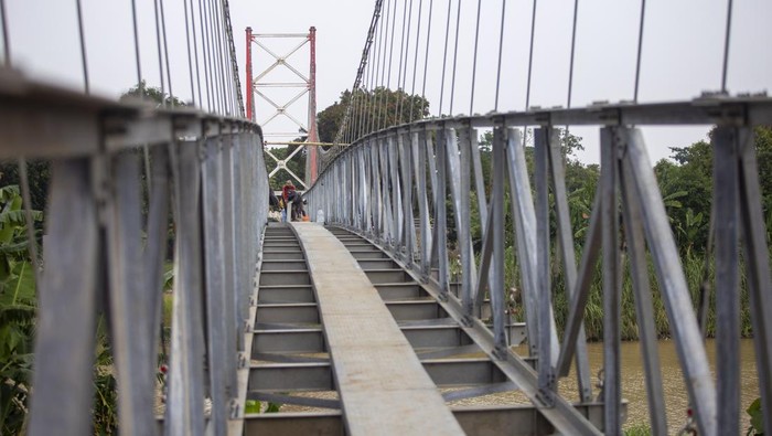 Pekerja menyelesaikan pembangunan jembatan gantung di Jatibarang, Indramayu, Jawa Barat, Rabu (27/12/2023). Kementerian PUPR membangun sebanyak 558 jembatan gantung selama periode 2015-2023 di Indonesia dalam rangka mempermudah konektivitas antardesa. ANTARA FOTO/Dedhez Anggara/tom.